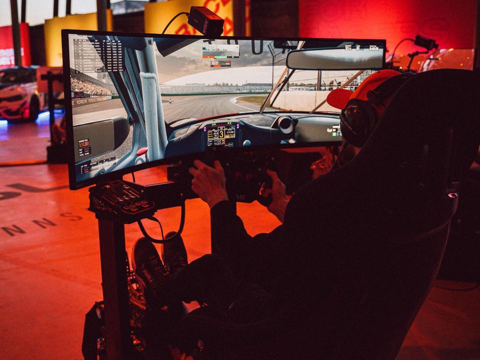 Людина їде в Rennsport із вигнутим екраном, кермом і педалями.