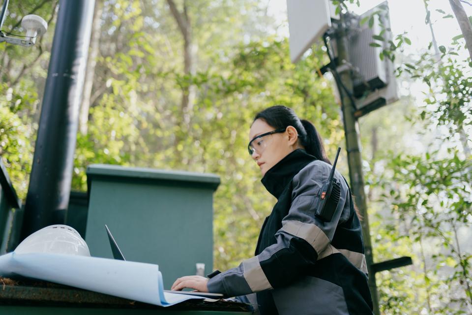 La ingeniera asiática está depurando la estación base de señal 5G