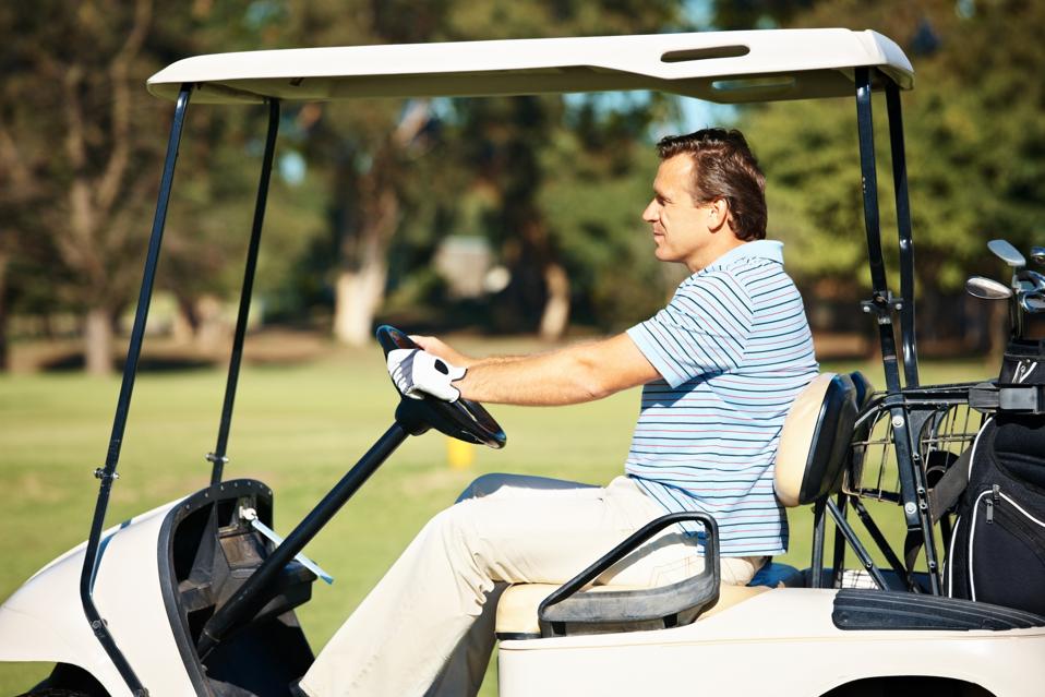 Mature golfer riding a golf cart