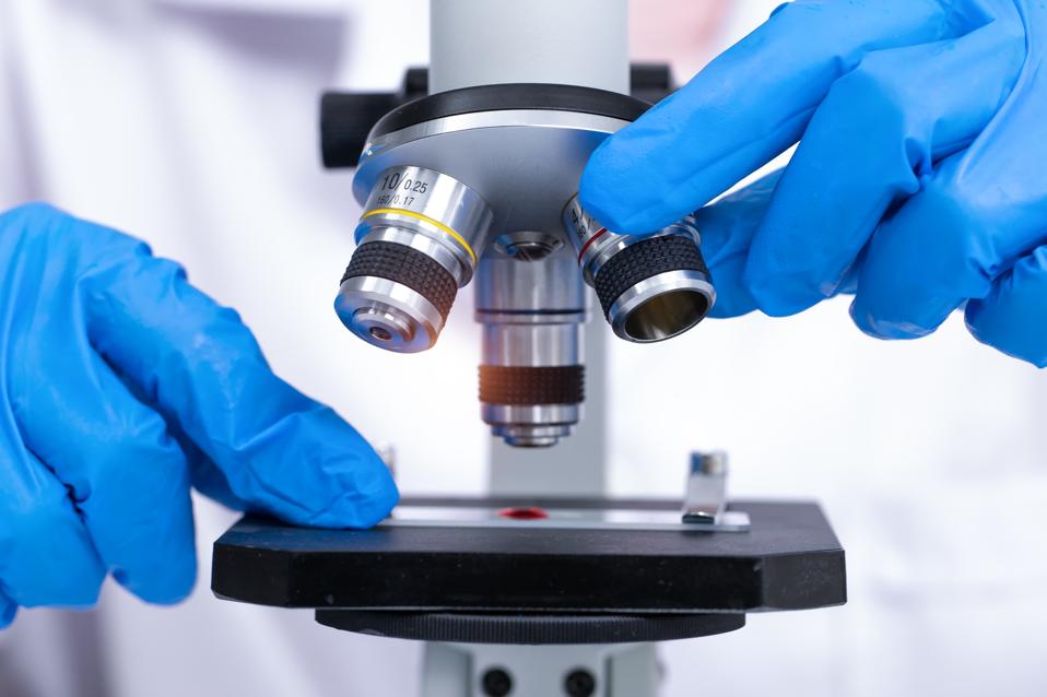 científico mirando a través de un microscopio en un laboratorio. Joven científico investigando.