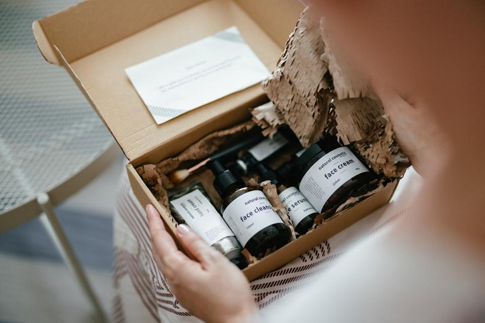 Anonymous Woman Holding a Gift Box and Looking at Beauty Cosmetics Products Inside (Copy Space)