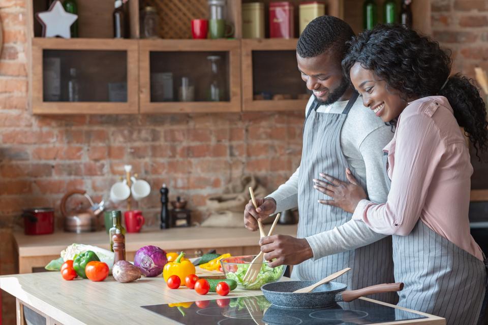 Alegre familia negra cocinando la cena juntos en la cocina