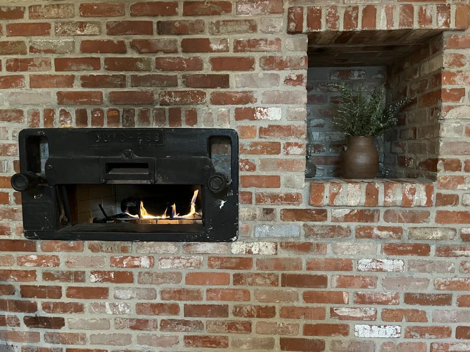 A Dutchess oven and an urn full of flowers embedded in a brick wall.