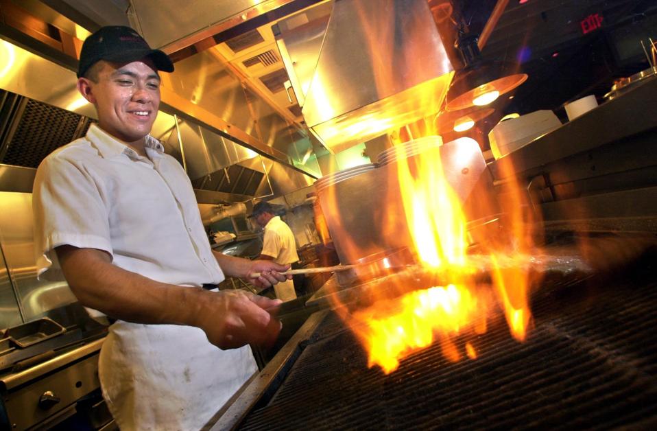 Chef Rodrigo Jasso grills an order of ribs over mesquite flames at the Wood Ranch BBQ & Grill. Ribs