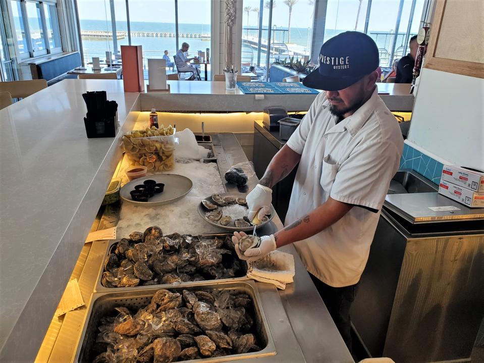 A man shucking fresh oysters at a restaurant