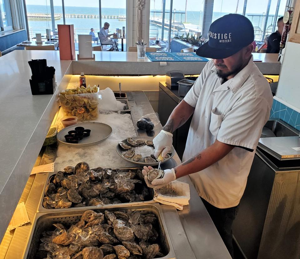 A man shucking fresh oysters at a restaurant