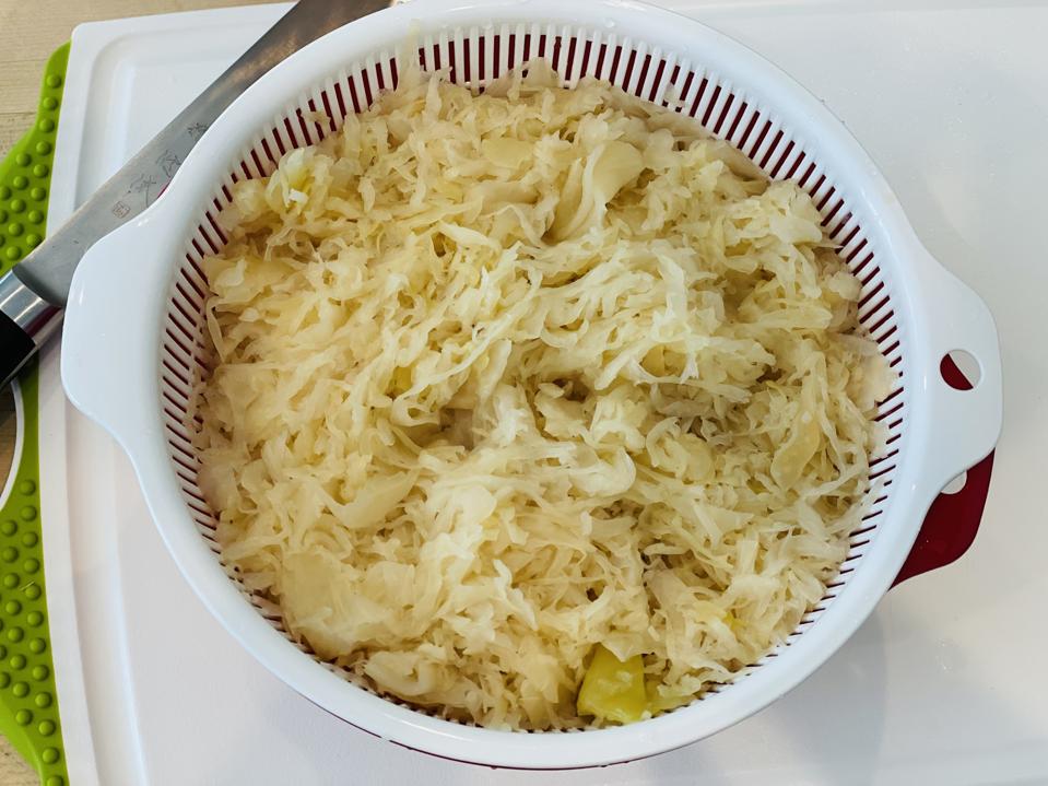 In this photograph by Elizabeth karmel, sauerkraut has been rinsed with water and is draining. Rinsing the sauerkraut with water and draining it before making the stew gives it a milder taste and removes some of the brine. Rinse and Drain 0704