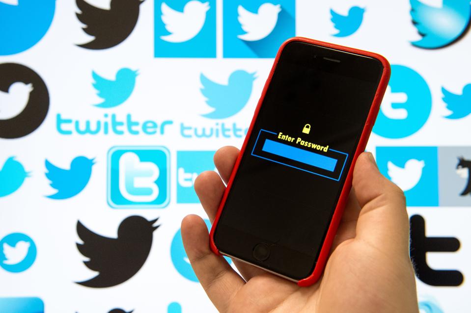 Twitter logos in background, smartphone with 'enter password' in foreground