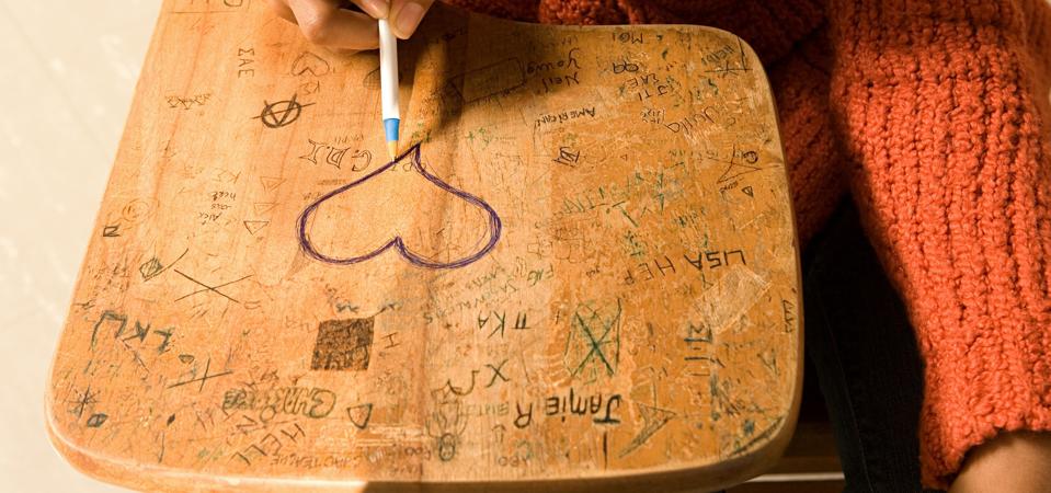 Student drawing a heart on her desk