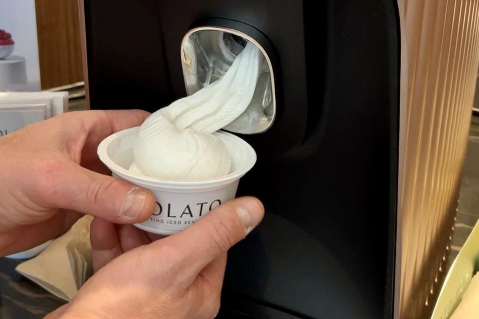 A person holds a cup as a Solato machine fills it with coconut gelato at the LAX Sky Club.