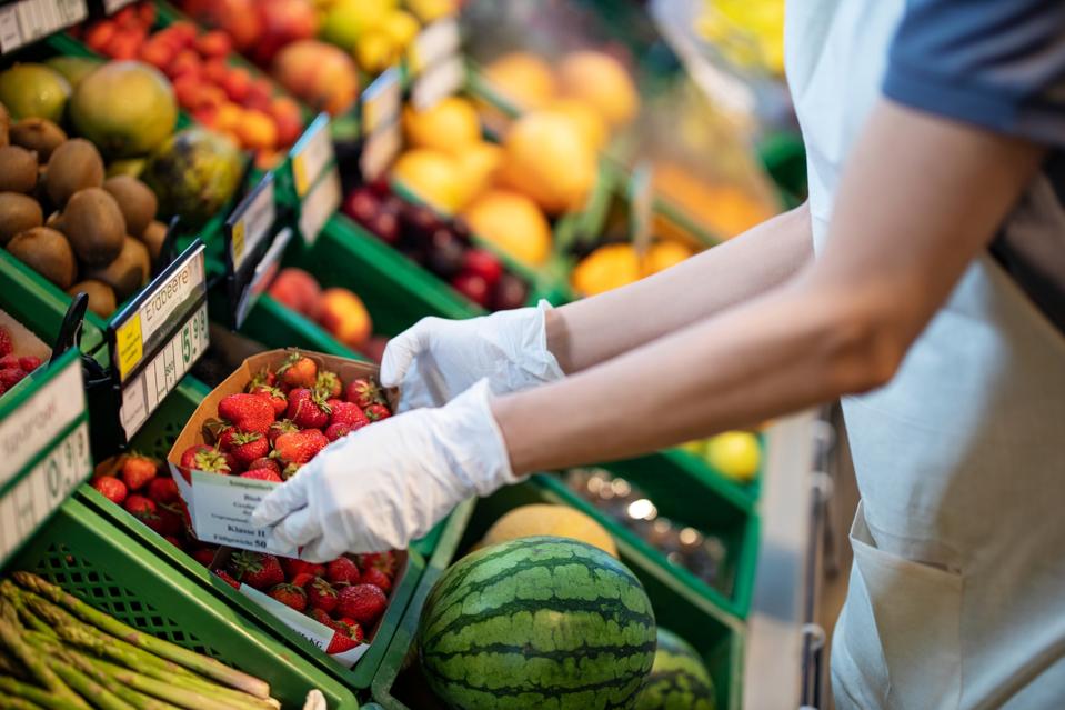 Store assistant at supermarket arranging fruits on shelve