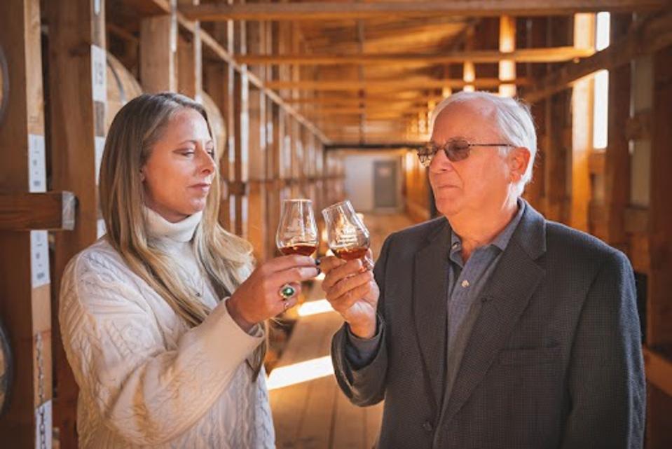 Louise McGuane and John Rhea toasting with a glass of whiskey