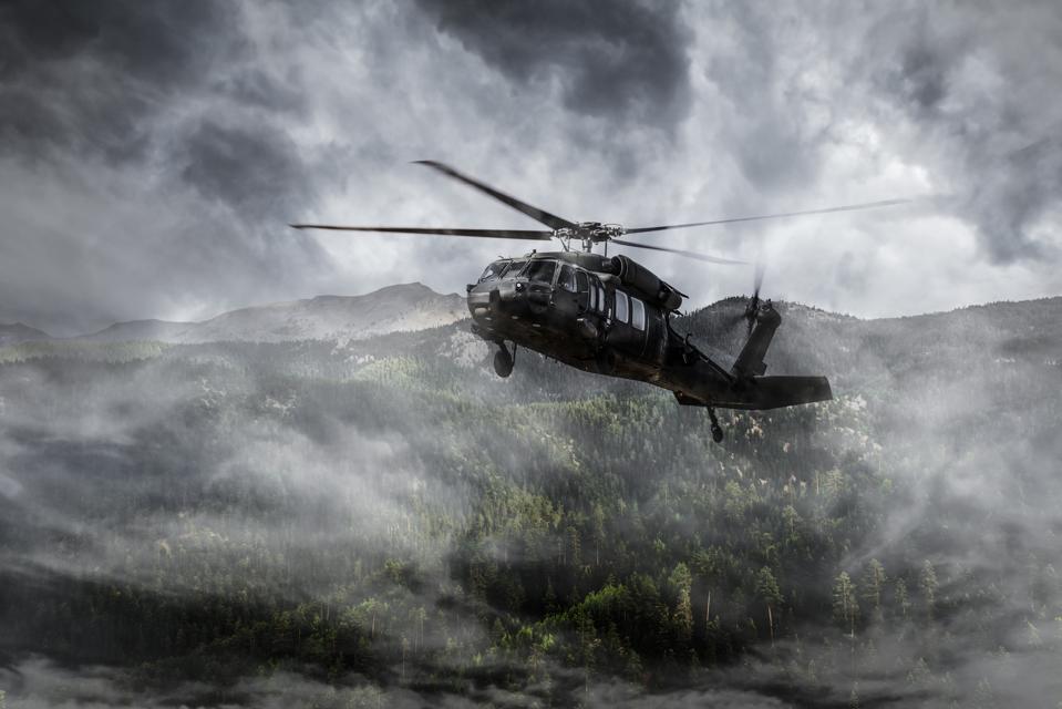 Army Helicopter Flies over Foggy Mountains