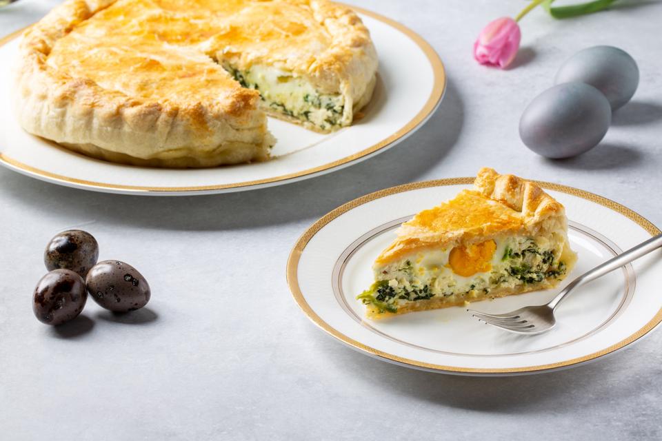 Torta Pasqualina. Traditional Italian savory Easter pie with spinach, chard, ricotta and whole eggs on gray background.