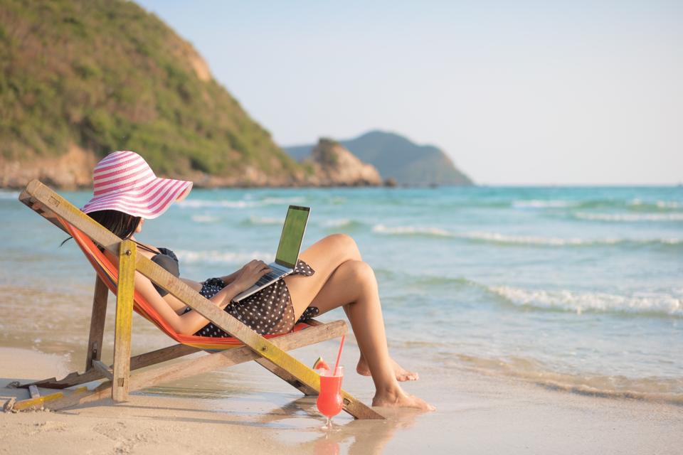 Professional woman, working with a laptop on the beach