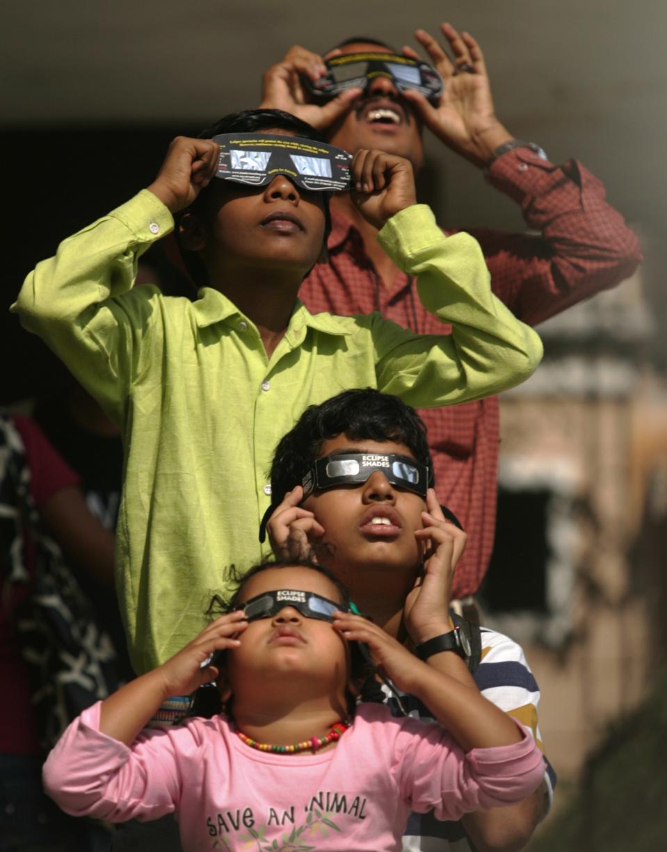 People use solar viewers to view an annular solar eclipse at the Nehru planetarium in Mumbai in December 2010. (Photo by Satish Bate/Hindustan Times via Getty Images)