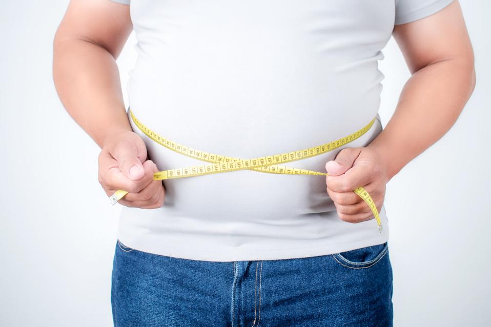 Overweight men measure his belly fat on a white background.