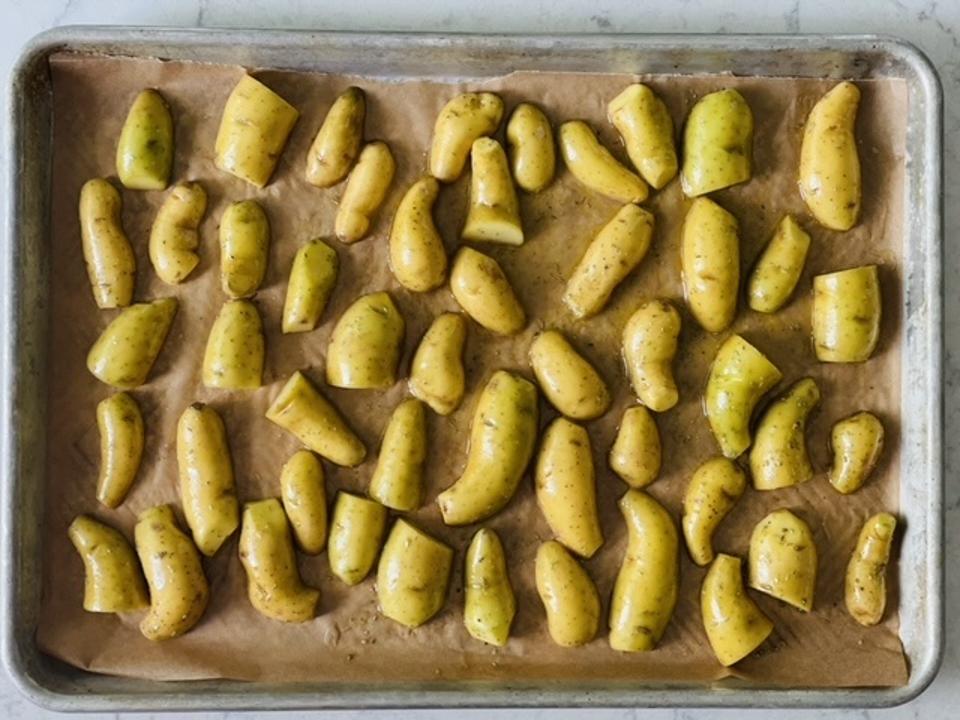 In the photograph by Elizabeth Karmel are petite fingerlings sliced in half and placed cut side down on a parchment-lined sheet pan. The key to these restaurant quality crispy potatoes is roasting them cut-side down the entire time.