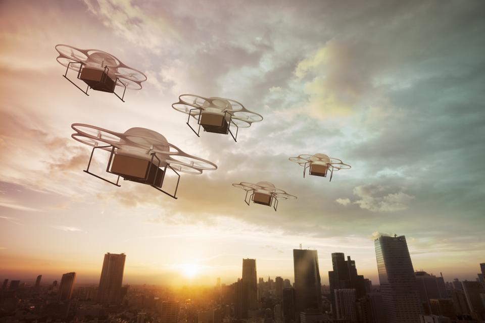 Five delivery drones flying above the city at sunset