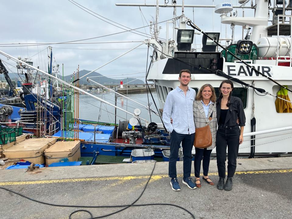 people posing on a dock in front of a fishing vessel