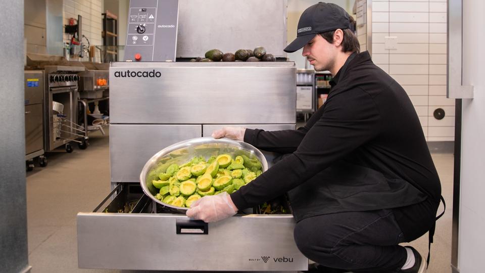 A Chipotle team member removing avocado fruit from the Autocado