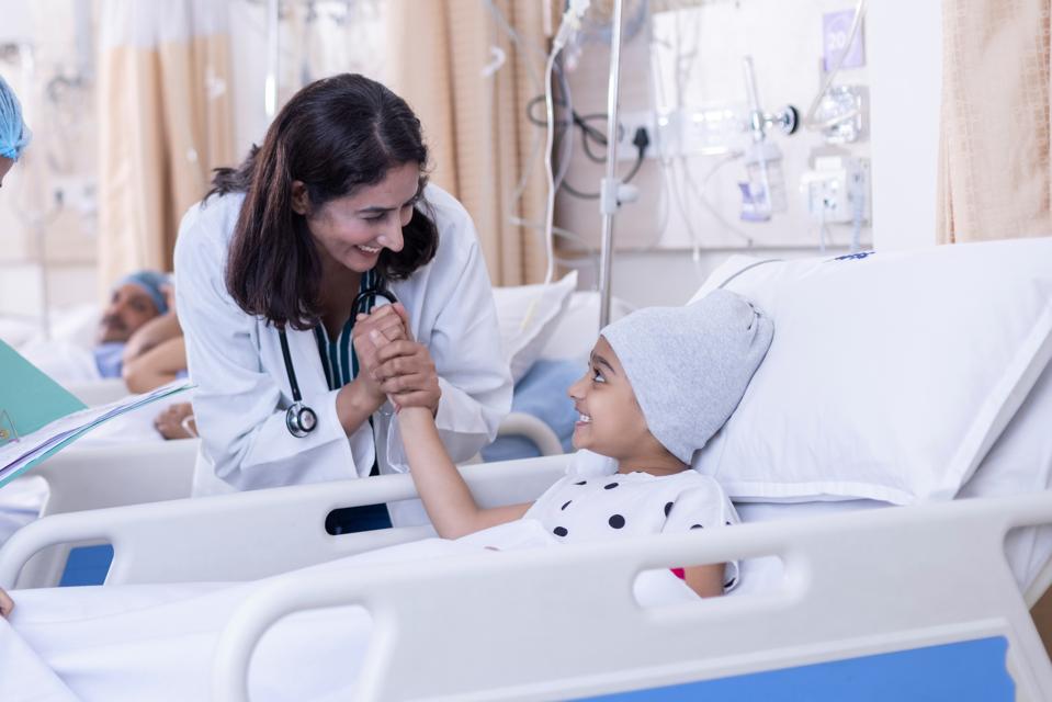 Female doctor giving high five to little girl patient at hospital.