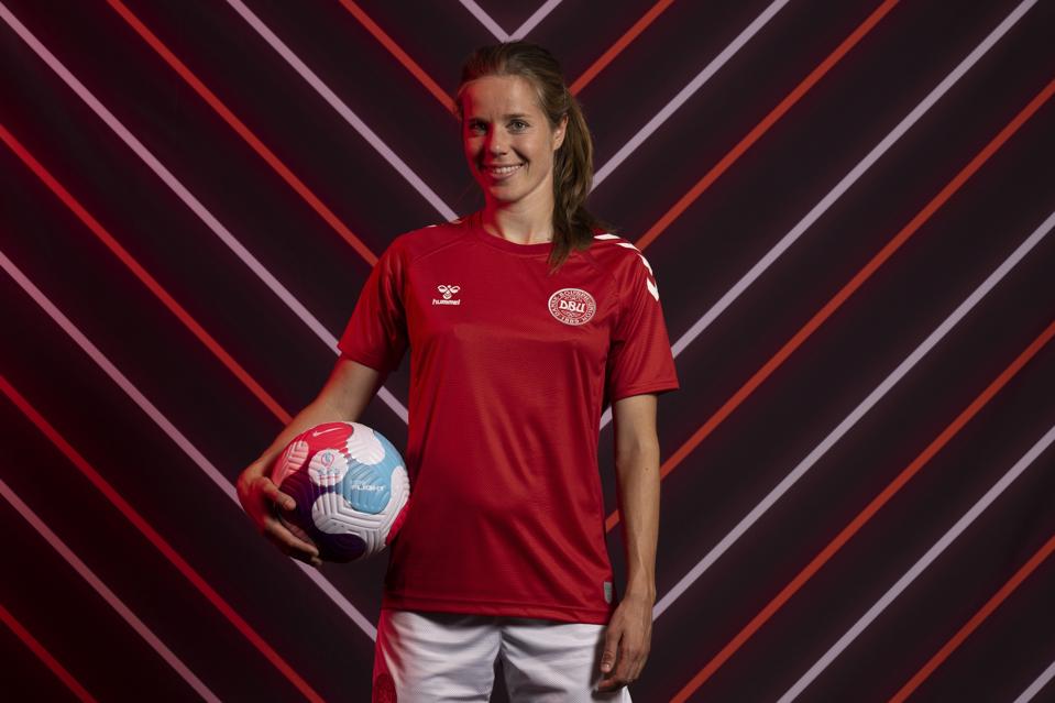Sofie Junge Pedersen holds a soccer ball in her right hand a poses for a picture.