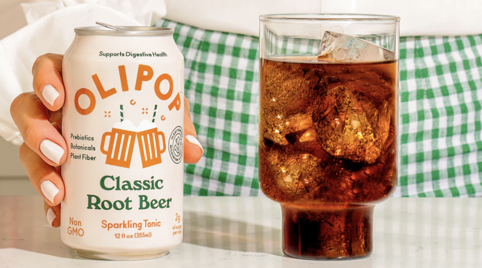 can of Olipop root beer next to a glass