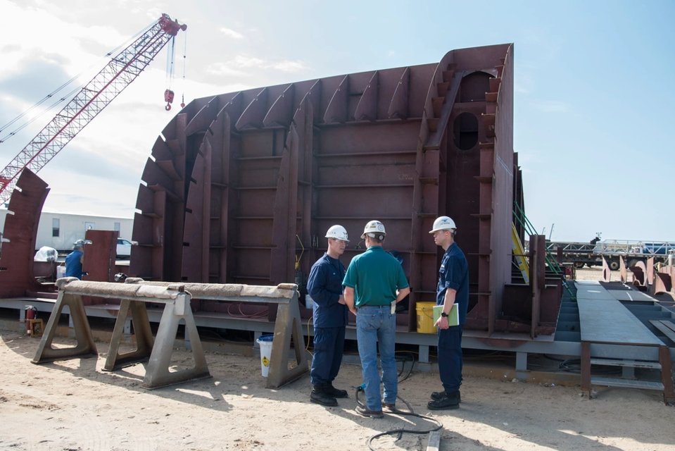 Coast Guard officials eye construction progress at Eastern Shipbuilding Group.