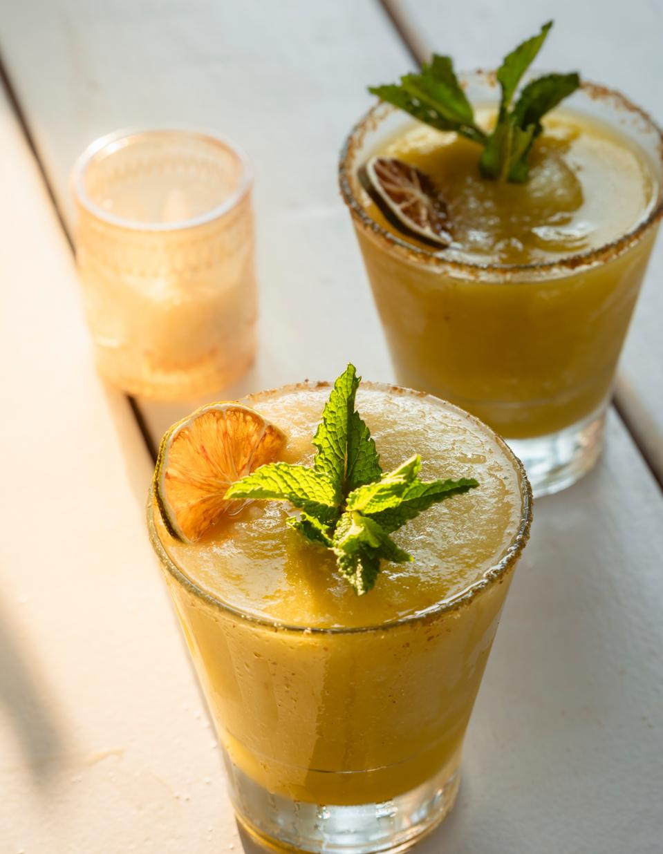 Two frozen cocktails garnished with mint and lime
