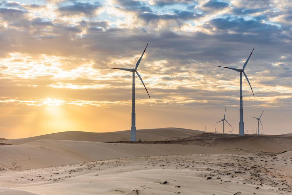 Wind turbines in a desert landscape at sunset.