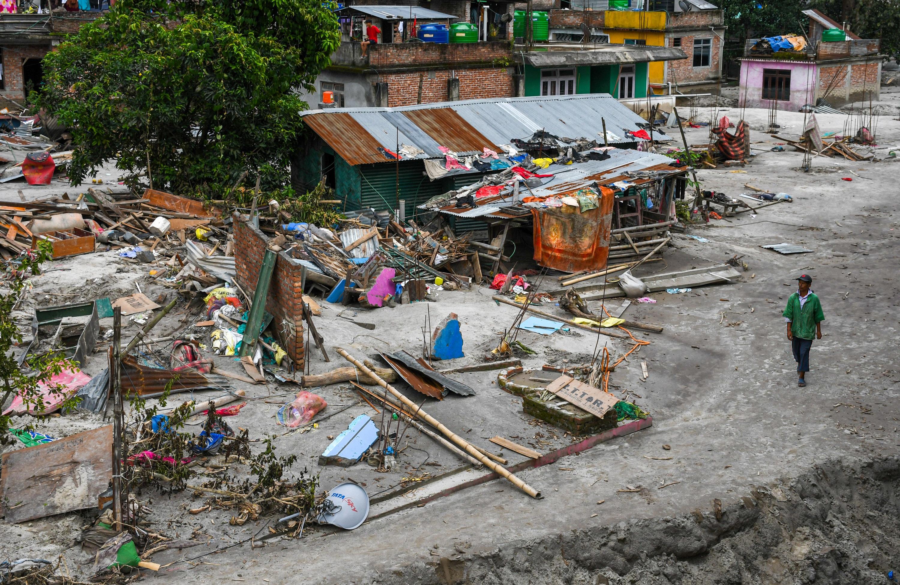 A man walks past flooded houses in the flood-affected area...