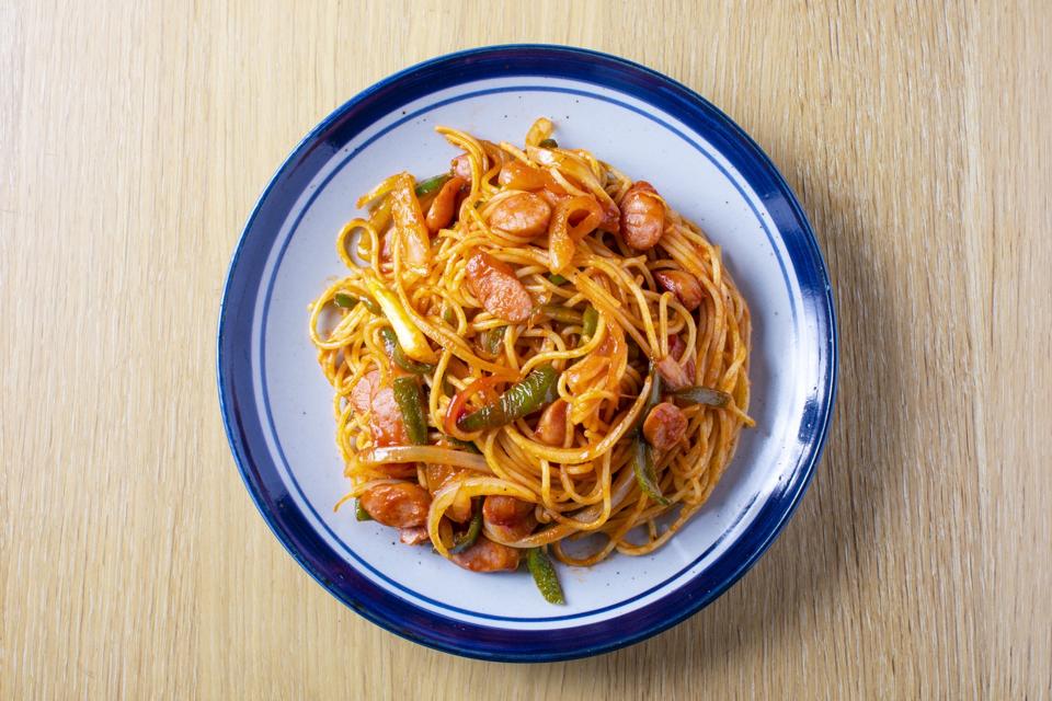 Japanese pasta dish, spaghetti (Naporitan) recipe. Naporitan on a plate is placed on a light wood grain table.