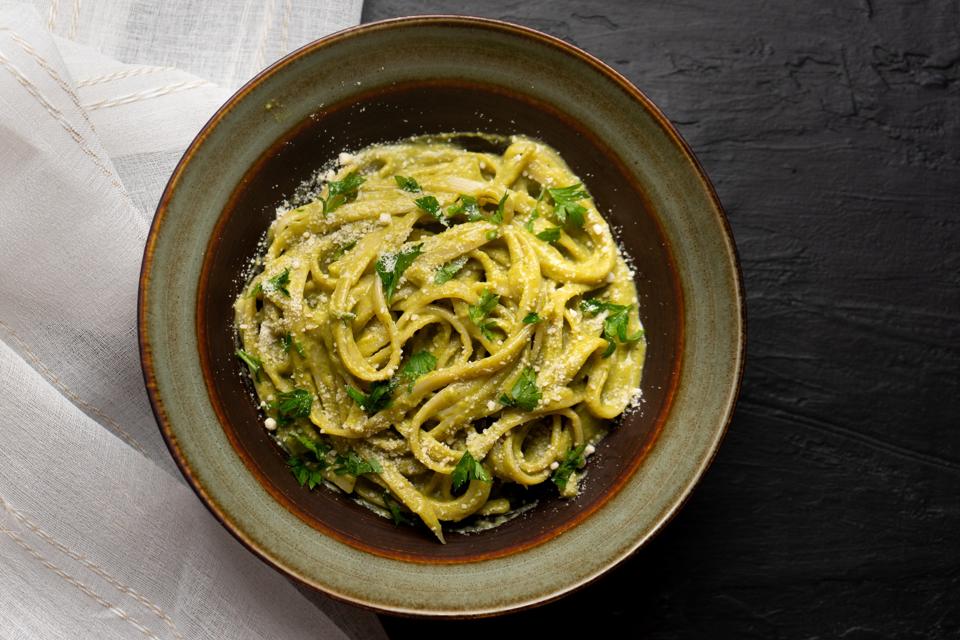 Creamy green pasta with poblano pepper and parmesan cheese on dark background
