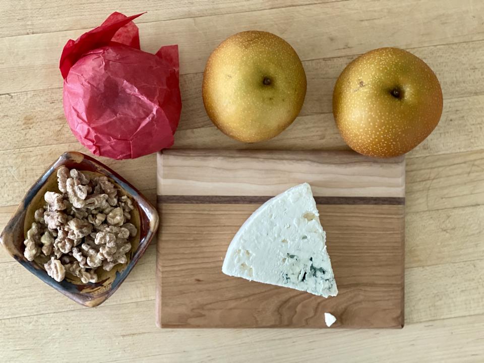 Asian Pears elevate the classic combination of pears, blue cheese and walnuts in this three-ingredient appetizer. In this photograph by Elizabeth Karmel are three Asian Pears, a triangle of blue cheese on a small cutting board and sprouted walnut halves.