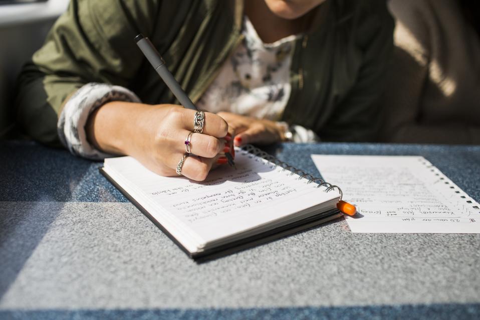 Midsection of businesswoman writing on diary in train