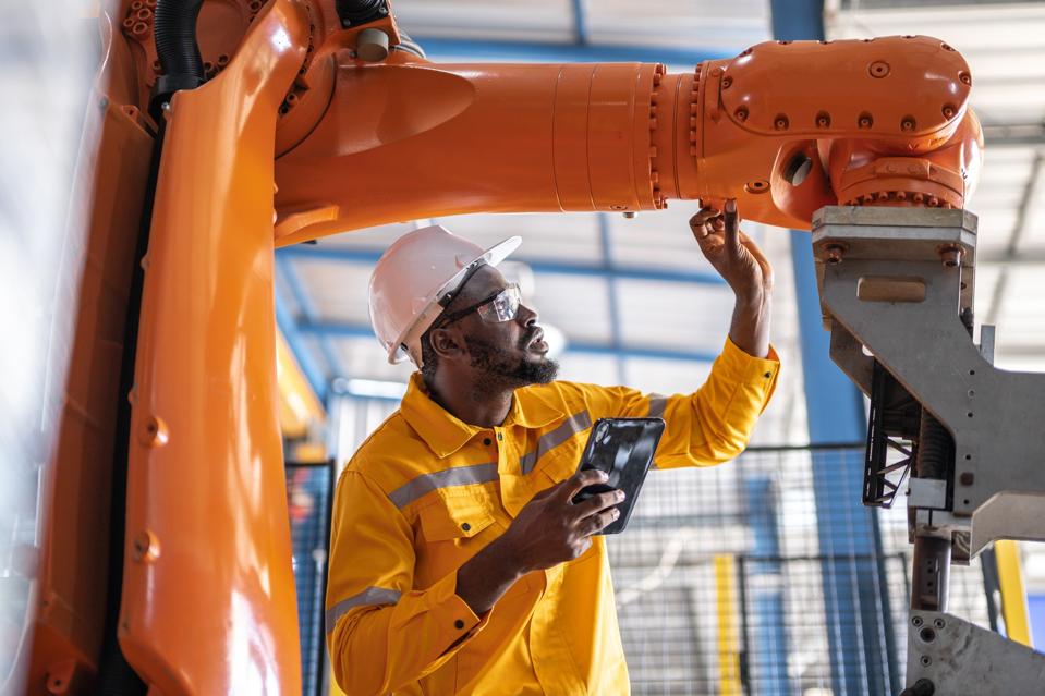 African engineer with tablet inspection the Robotic arm and working at manufacturing process