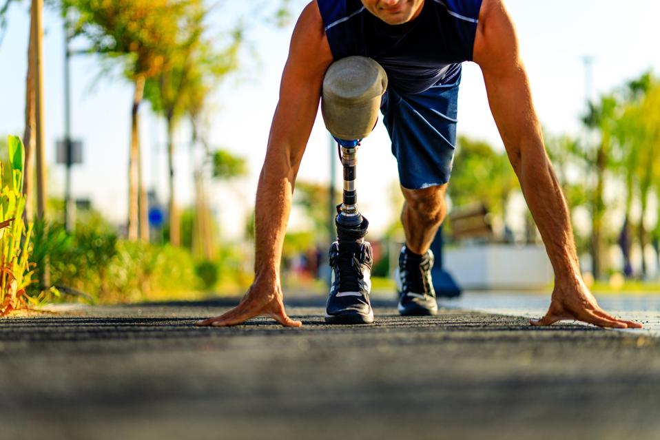 disabled athlete man with prosthetic leg starting to run at the beach on a treadmill outdoors at sunset