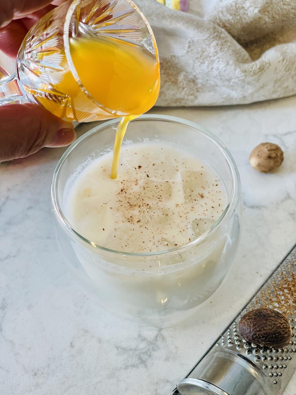 It is traditionally served chilled in small glasses (Like shot glasses) but I like to serve it over ice as it is seen here. My version of Coquito is shown in this photo with a shot of Chinola liqueur being poured on top.