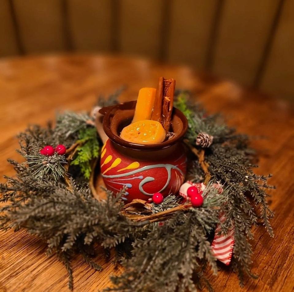 ponche navideño in a clay mug surrounded by a wreath
