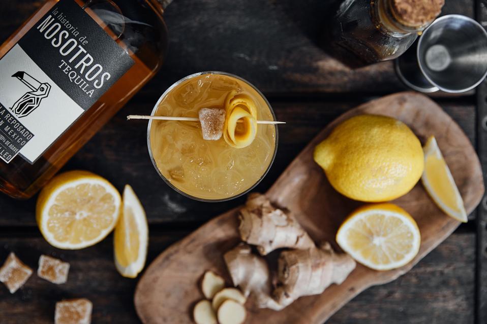 Nosotros Tequila bottle with a ginger and lemon cocktail