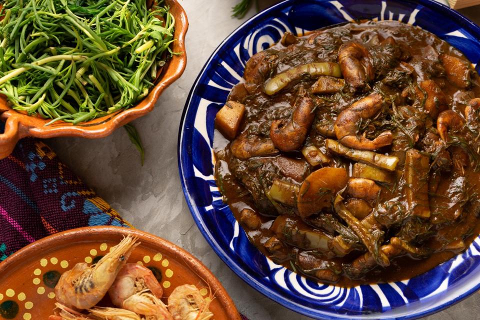 Mexican romeritos with mole sauce and shrimp on a gray background