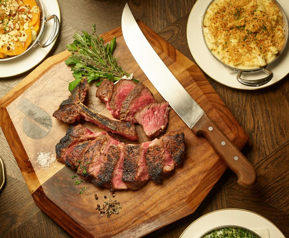 Sliced Tomahawk steak on a wooden board with knife
