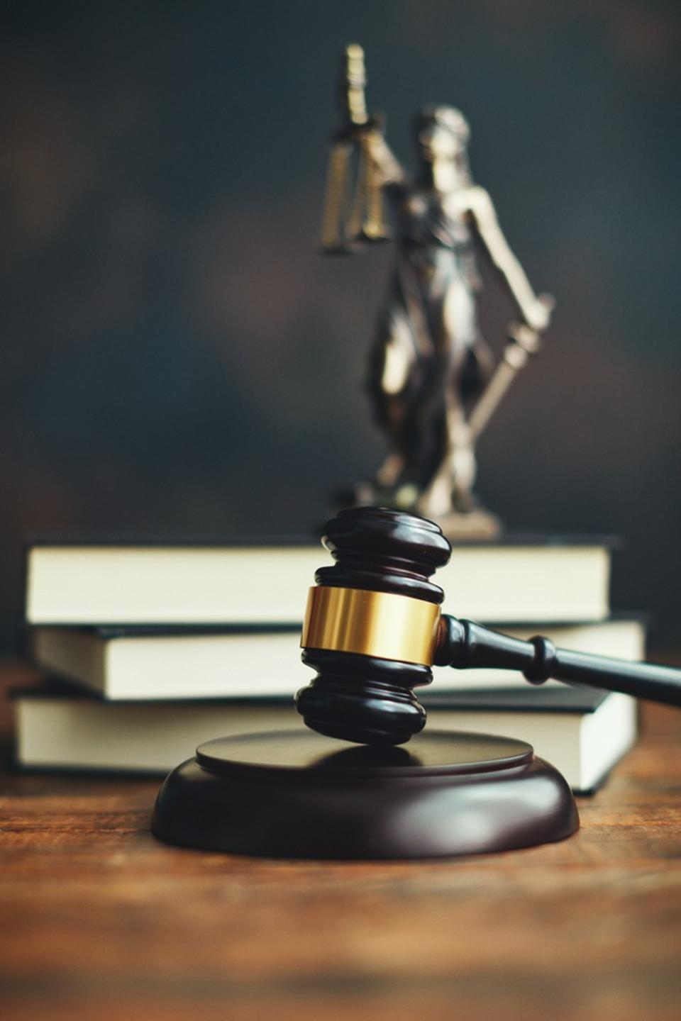 Gavel on desk with law books and Lady Justice