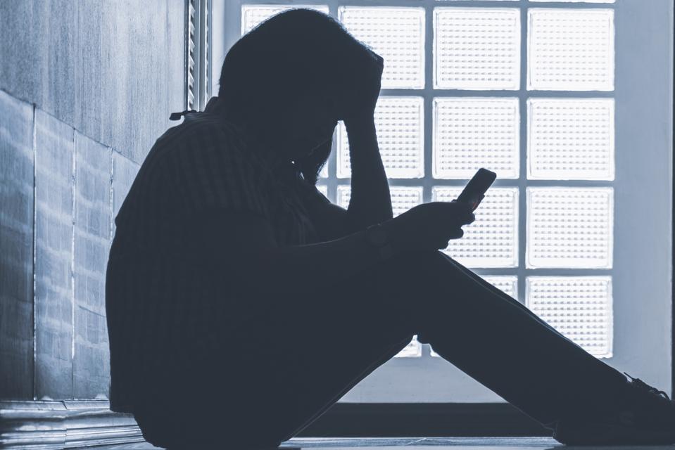 Depressed woman sitting alone on phone