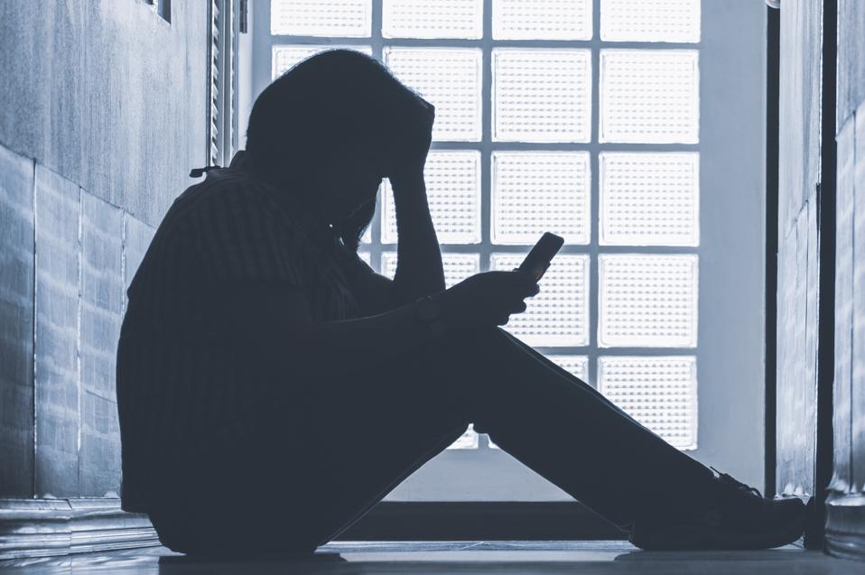 Woman on phone, head in hands.