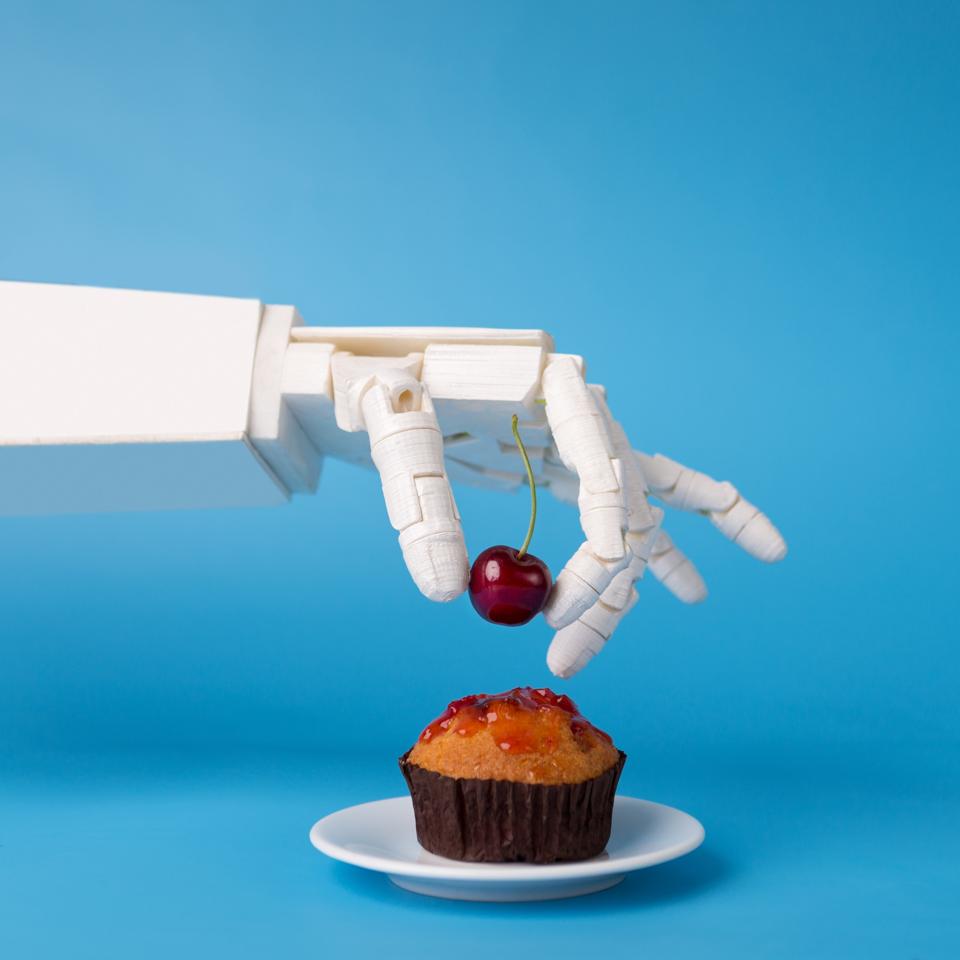Robot hand decorating sweet cupcake with fresh cherry