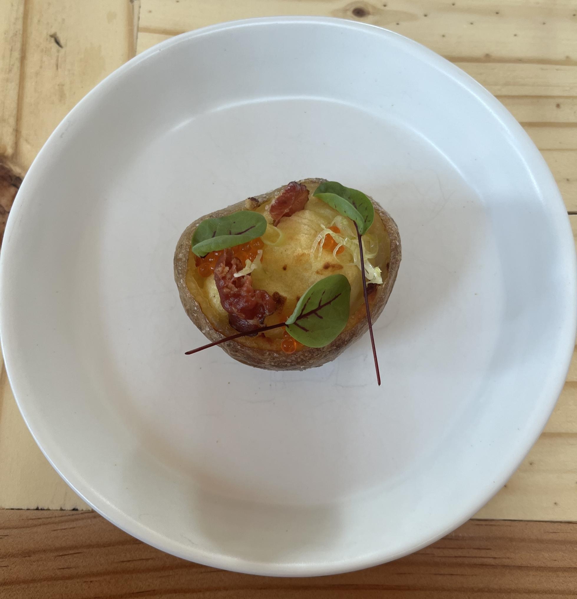 A baked potato topped with herbs on a large white plate.