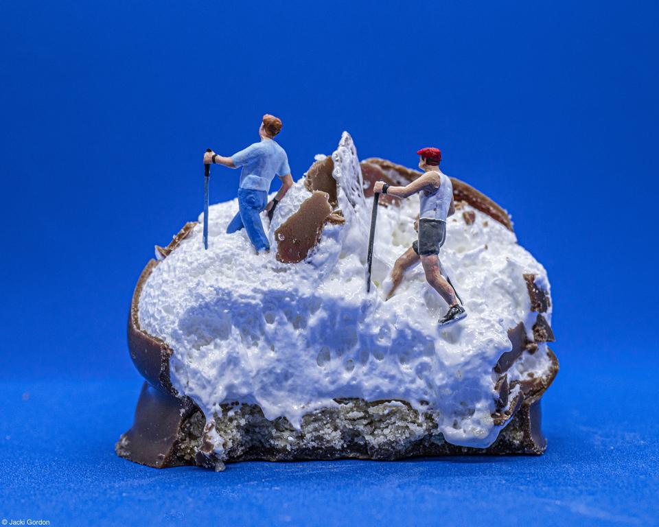 Two small figures of walkers on an open tea cake looking like snow.