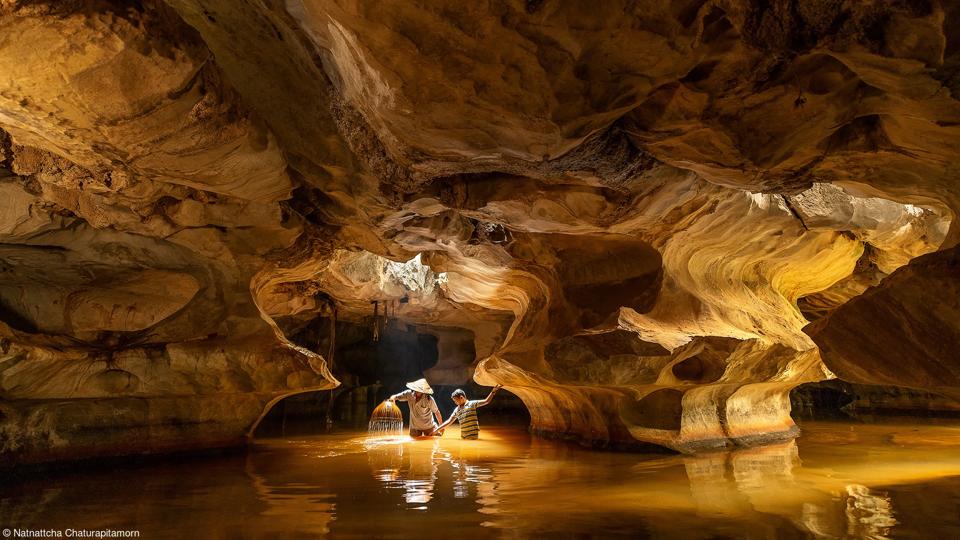 A local father and son fishing with sticks in a cave in Thailand.